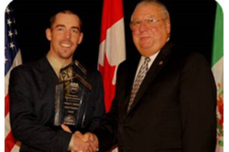 Inspector Richard Robinson, left, accepts his award from CVSA president Francis France.