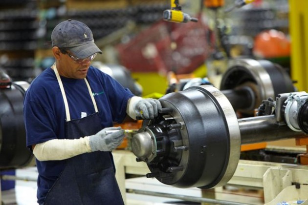 A plant employee assembles a trailer axle.