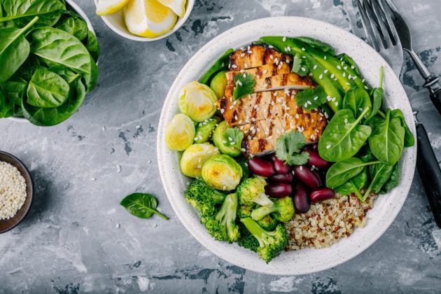 Healthy buddha bowl lunch with grilled chicken, quinoa, spinach, avocado, brussels sprouts, broccoli, red beans with sesame seeds alternate text for this image