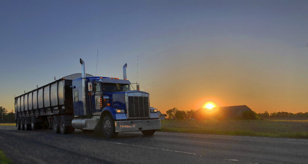 Semi-Truck Leaving a Farm in the Sunrise alternate text for this image