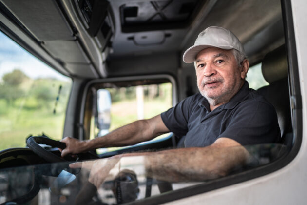 Portrait of a senior male truck driver sitting in cab alternate text for this image
