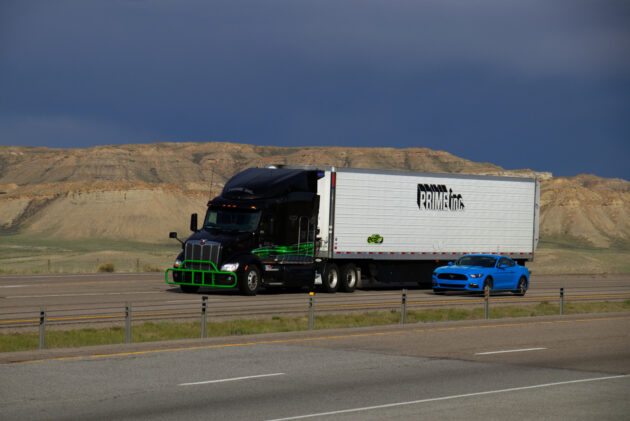 “Prime Inc” Semi-Truck and Blue Ford Mustang alternate text for this image