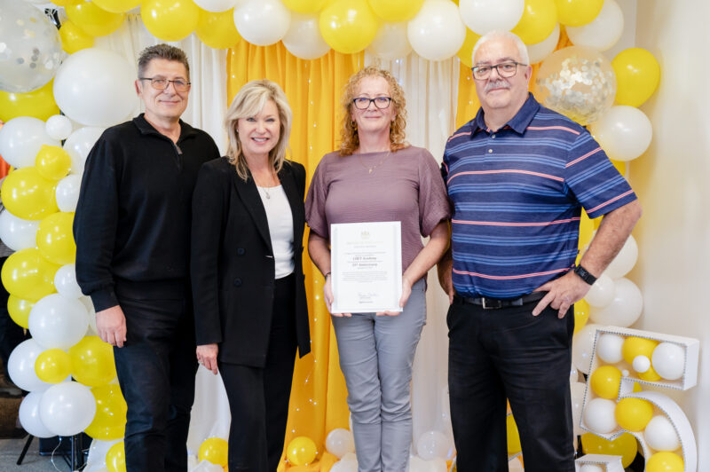People standing behind balloons during CHET anniversary celebrations.