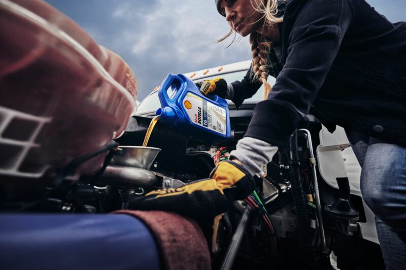 Woman pouring oil into a truck engine