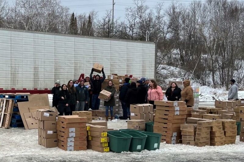 Picture of people with donated food in boxes near a trailer