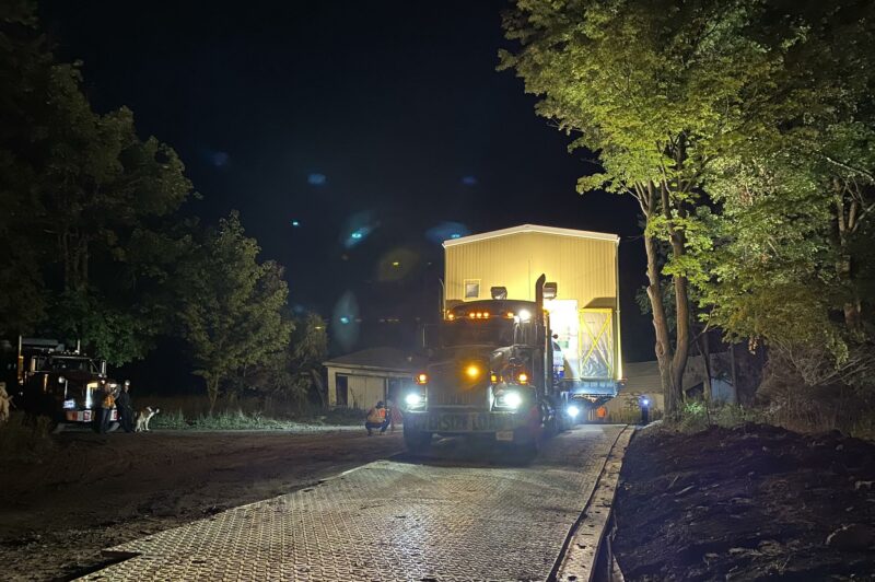 Picture of a truck moving an oversized load at night.