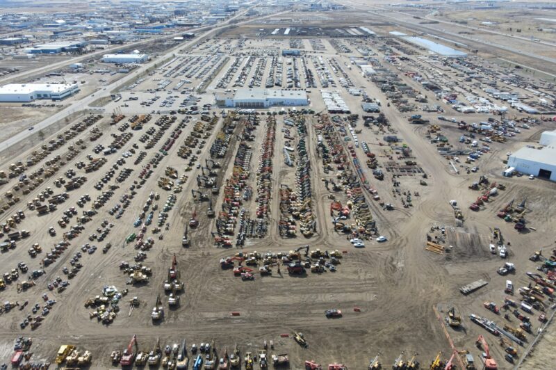 Vehicles and equipment parked in a huge lot.