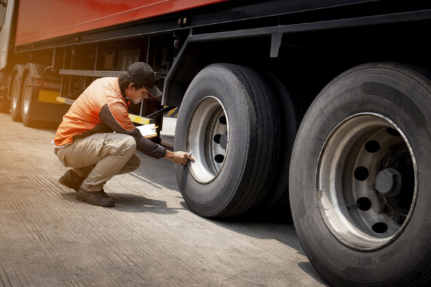 Truck driver inspecting safety daily check a truck wheels alternate text for this image