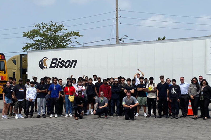 People in front of a Bison Transport truck and trailer