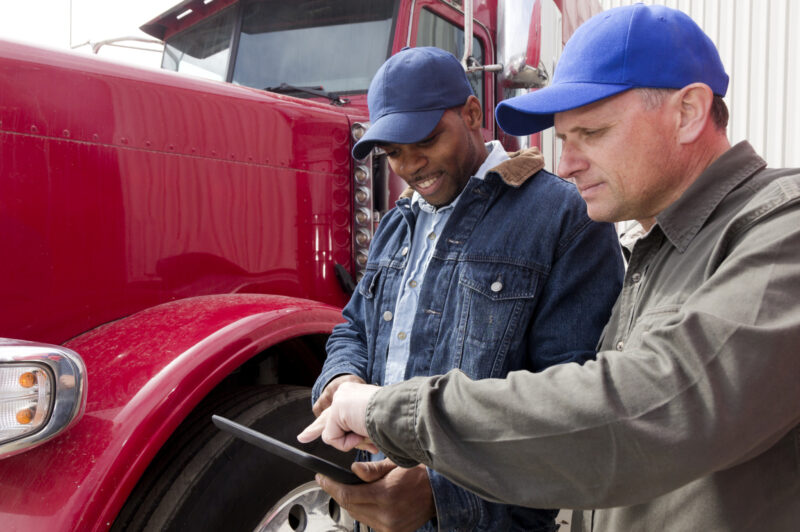 Men standing in front of a truck looking at a tablet