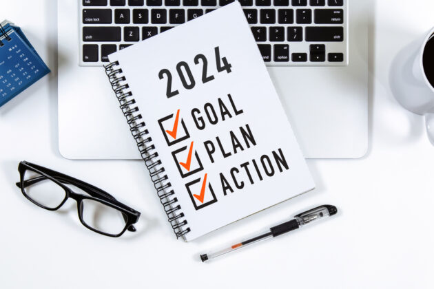2024 Goal, Plan, Action checklist text on note pad with laptop, glasses and pen. alternate text for this image