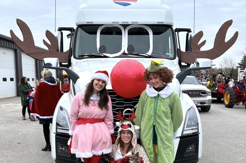 People dressed in Christmas costumes in front of a decorated truck