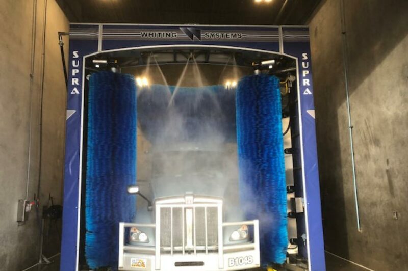 the image is of the truck being washed in between the brushes of the Autonomous Three Brush Gantry system