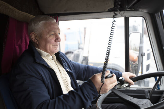 Elderly driver sitting in cabin of big modern truck