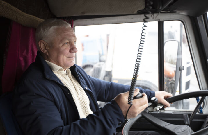 Elderly driver sitting in cabin of big modern truck