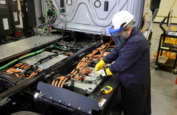 The image shows a person working on the battery electric truck