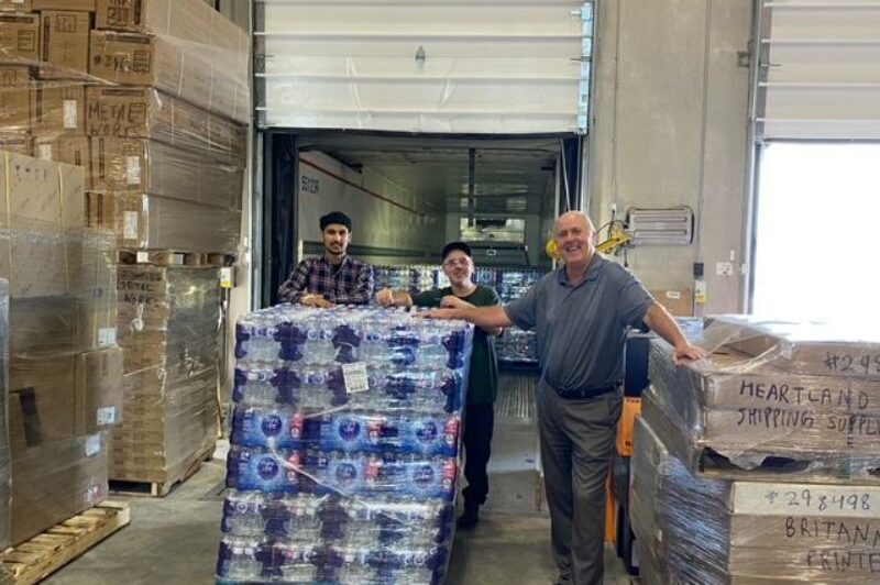 Stacey Jenkins and two other people with water packaged on the pallets