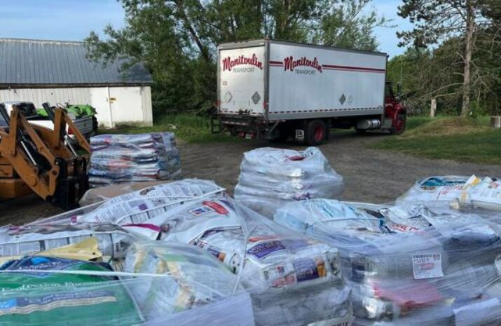 image shows a Manitoulin truck parked near large stacks of bagged items in an outdoor area