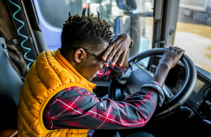 Tired male truck driver having a headache after working extra hours.