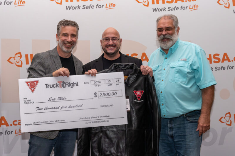Eric Melo in the middle with Rick Brown and John Farquhar presenting him with a check