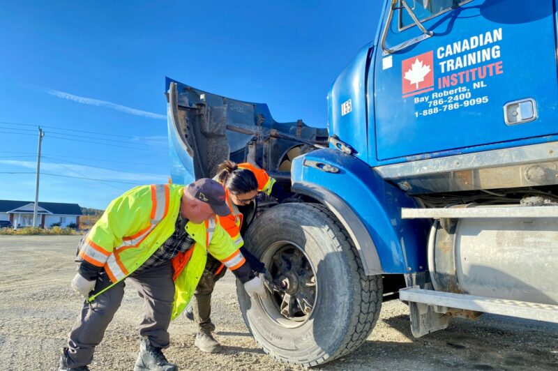 A student inspects a tire during a pre-trip inspection