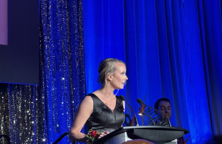 Stacey Large photo -- she is at the podium delivering a speech