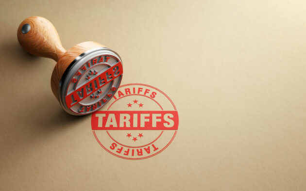 Wooden Tariffs Stamp Is Sitting On Recycled Paper Background alternate text for this image