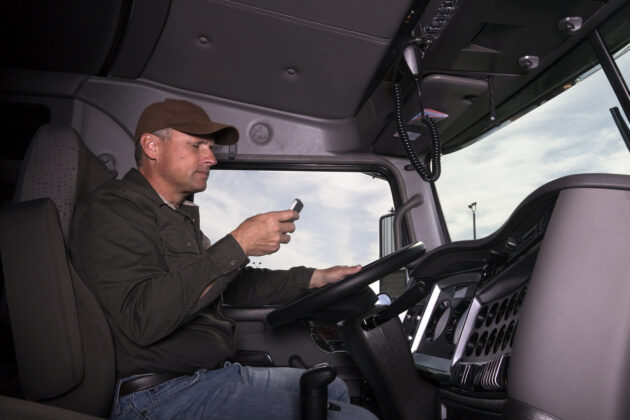 A truck driver texts while behind the wheel