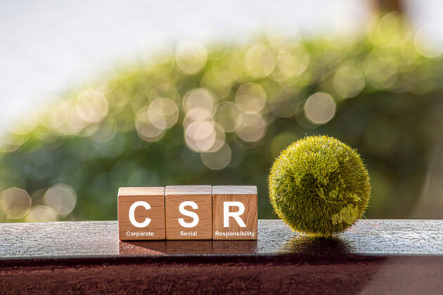 CSR (coporate social responsibility). words CSR on a woodblock and green world on a green background It is an idea for Corporate social responsibility and society activity concept. alternate text for this image