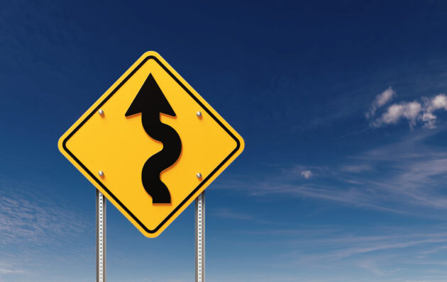 Left Winding Road Sign Before Blue Sky alternate text for this image