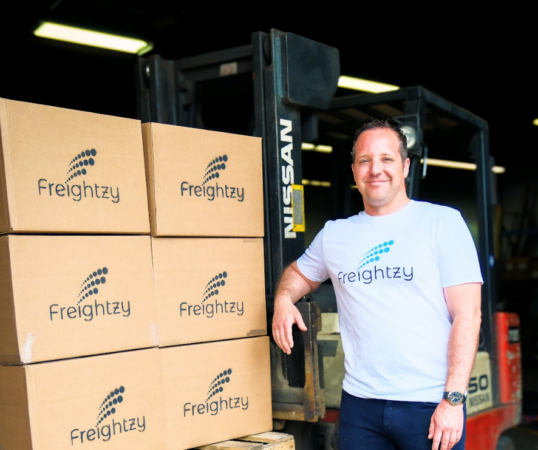 A person and a box of shipment with Freightzy logos