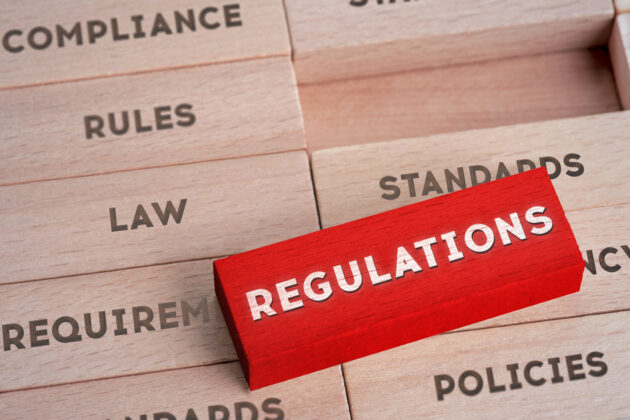 Regulations Concept with Wooden Blocks in Red Color alternate text for this image