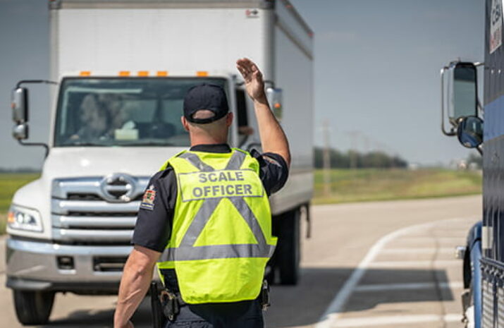 Picture of an officer directing a truck to a weigh scale
