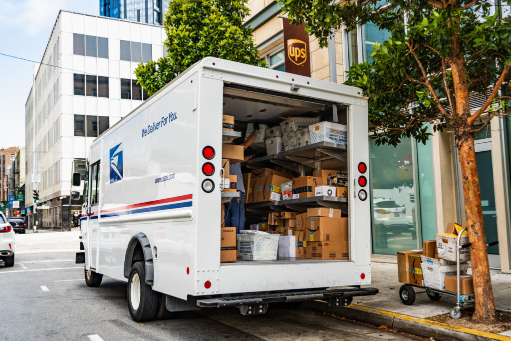 A postal truck in front of a UPS station.