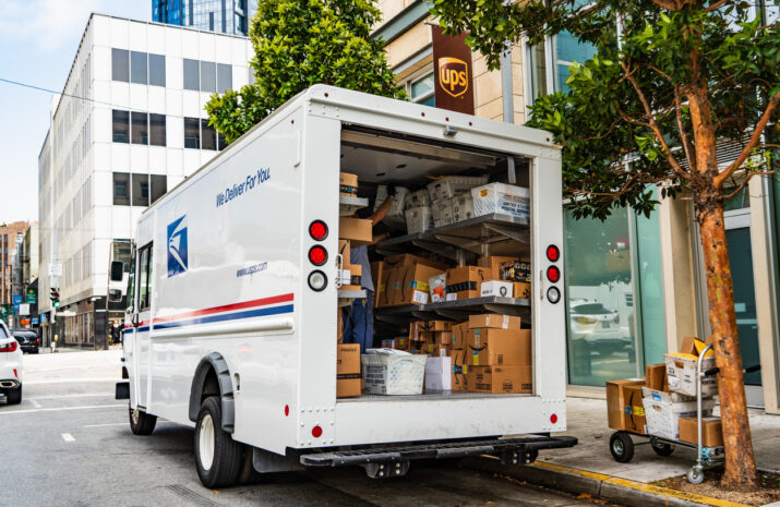 A postal truck in front of a UPS station.