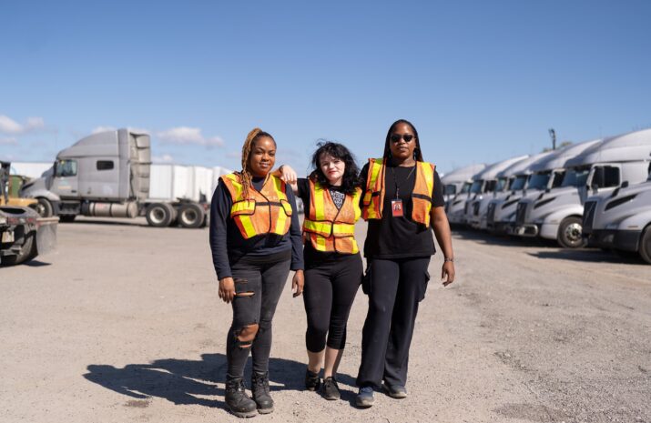 Three women in a truck yard