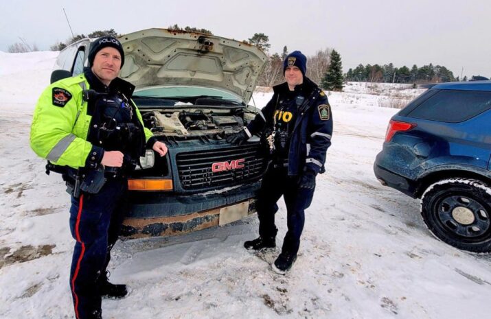 Picture of officers in front of a pick up truck
