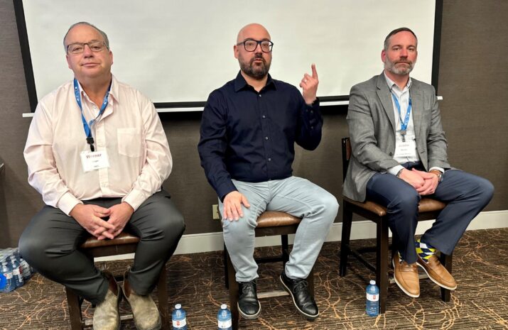 Three seated men during a panel discussion
