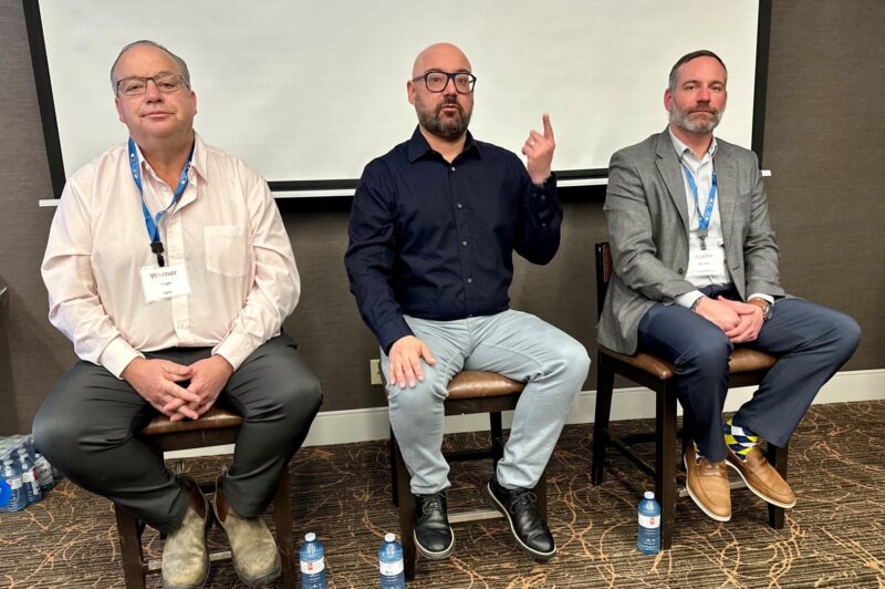 Three seated men during a panel discussion