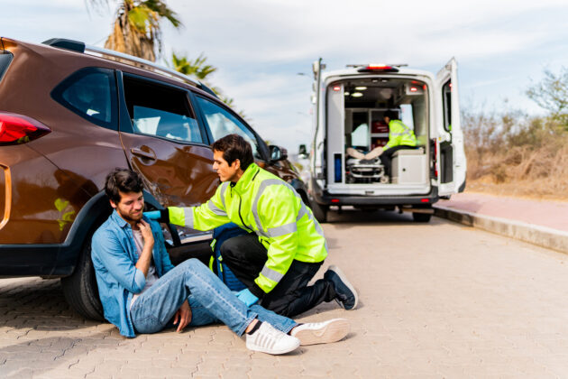 Paramedic assisting injured man after car accident outdoors alternate text for this image