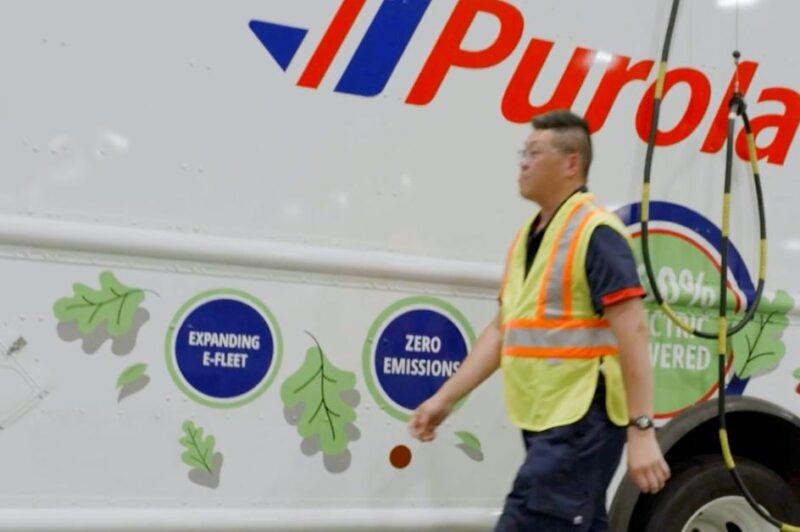A person in front of a Purolator electric truck