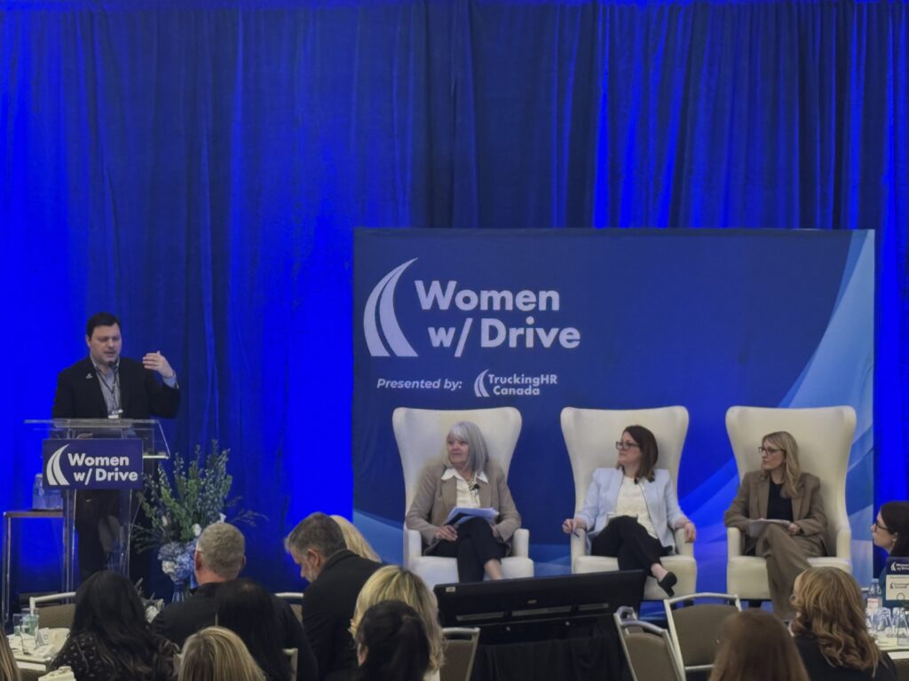 Three panelists and moderator on stage of WWD conference