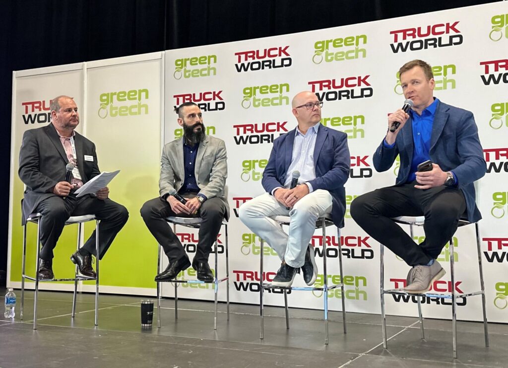 Four men sitting on stools on a stage