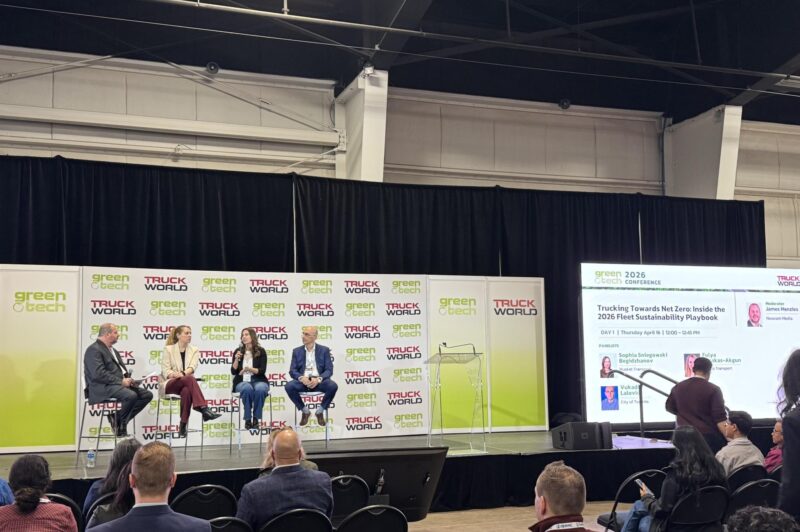 view from the back of the room, panelists on stage with people in attendance