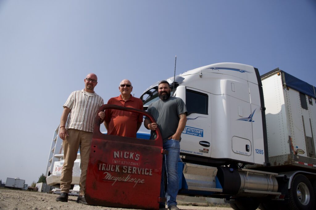 Jeff Rosenau, Dave and Brett Evasiuk in front of a modern truck with an old truck door from a 1936 truck 