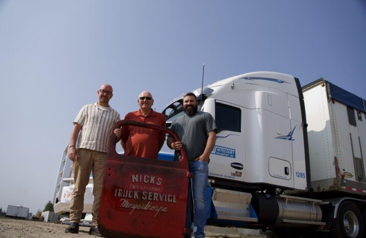 Jeff Rosenau, Dave and Brett Evasiuk in front of a modern truck with an old truck door from a 1936 truck