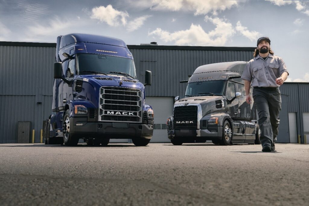 Driver walking in front of Mack trucks