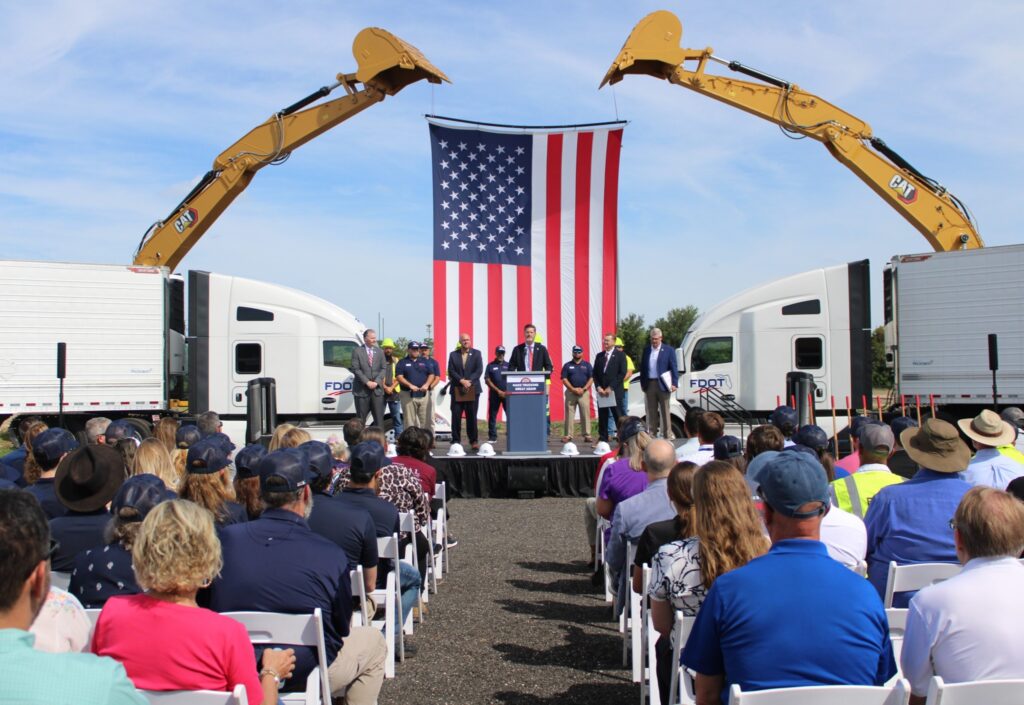 People standing on a stage with an American flag in the background