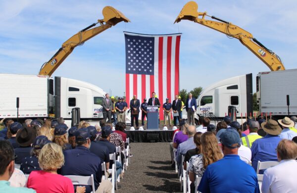 People standing on a stage with an American flag in the background