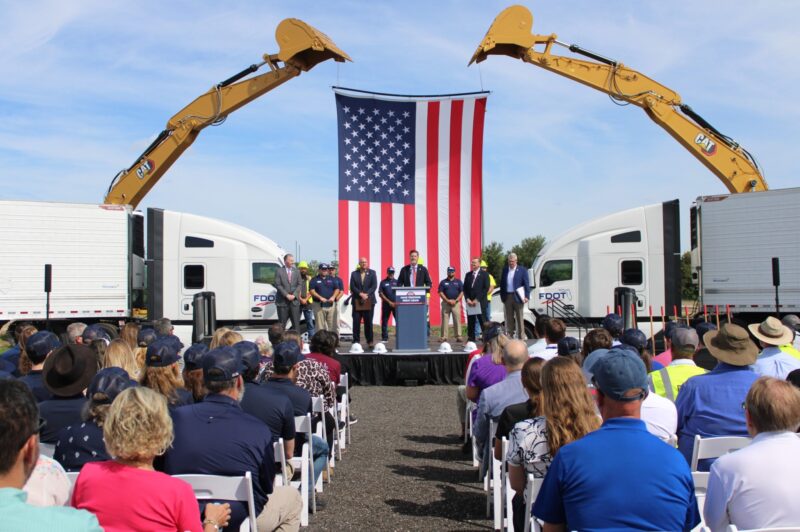 People standing on a stage with an American flag in the background